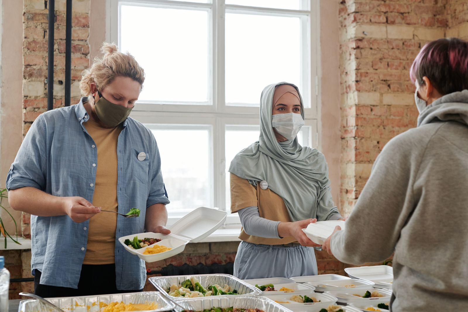 A volunteer serving a warm meal to a guest